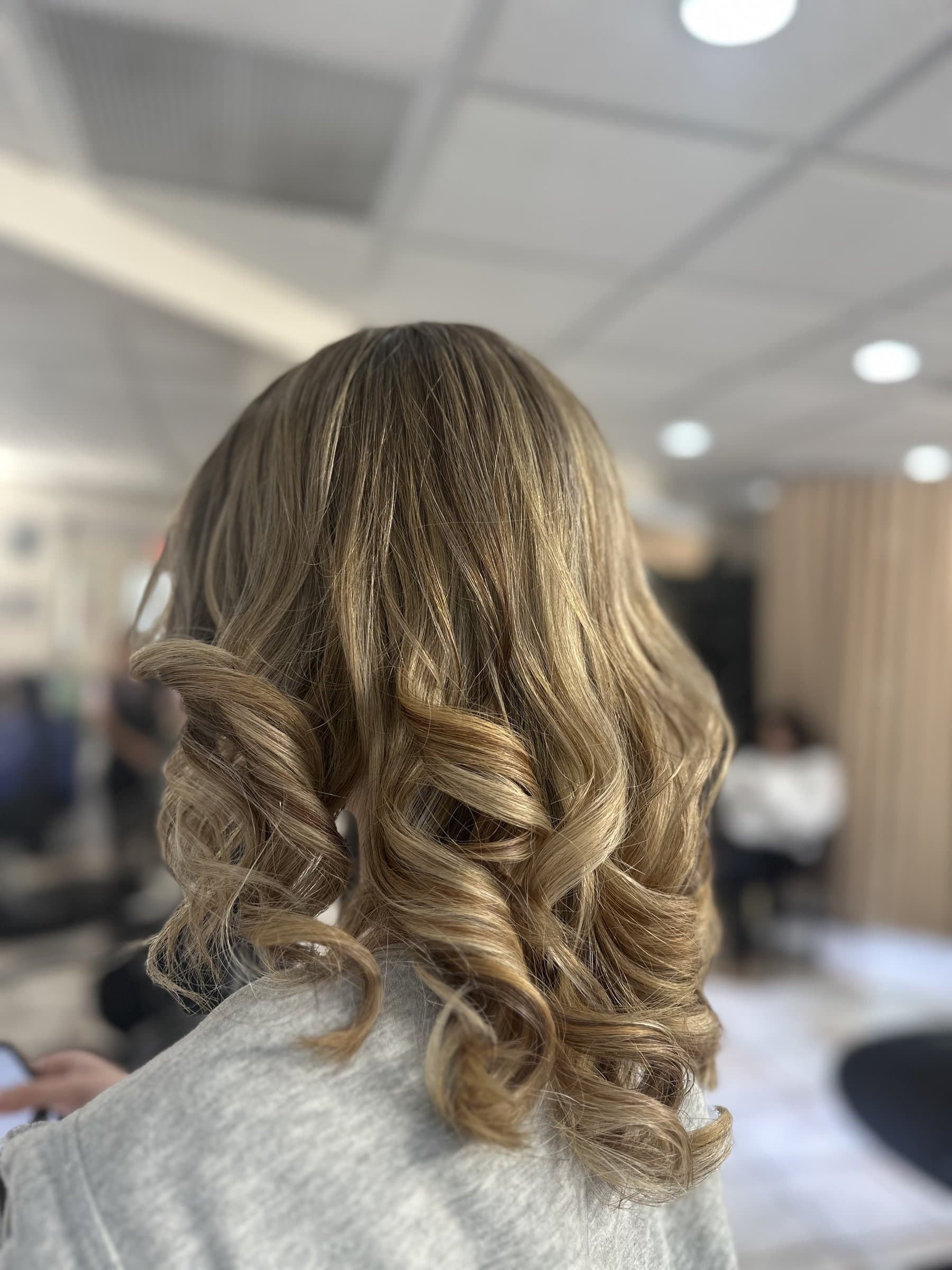 Voluminous blonde balayage curls styled at JBELLA Hair Salon